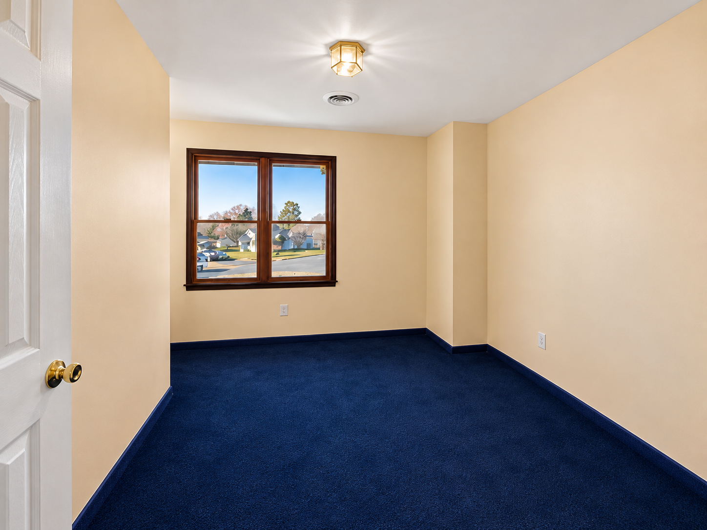 Basement room before finishing with navy carpet and beige walls