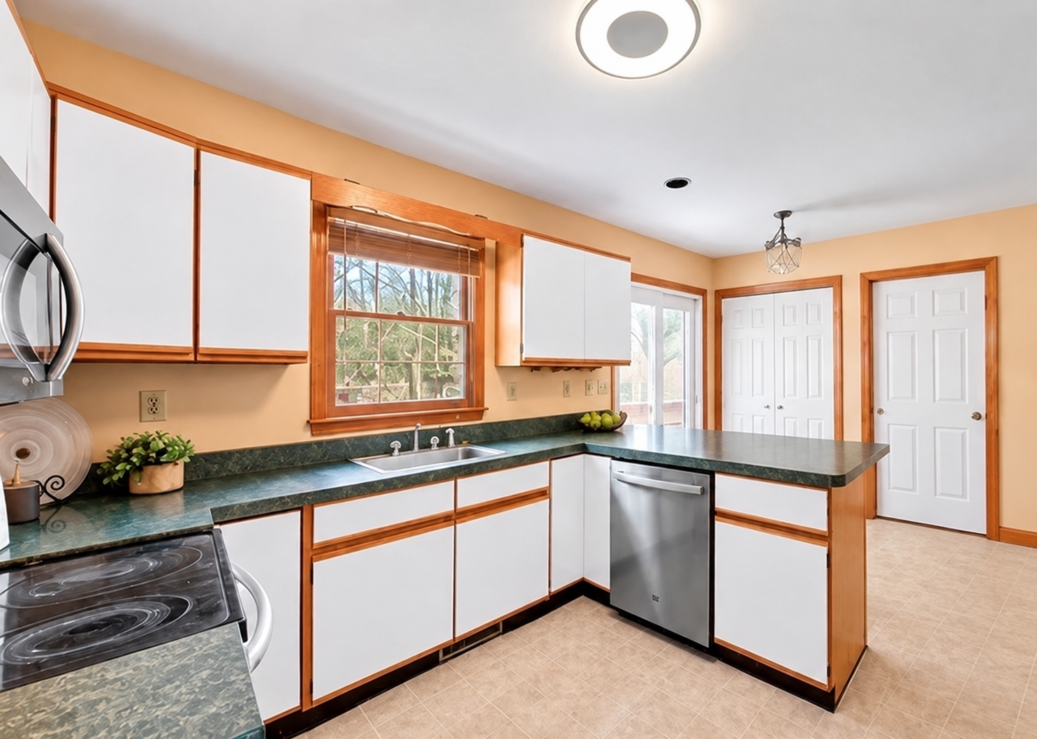 Kitchen before renovation with wood-trimmed cabinets and tile flooring