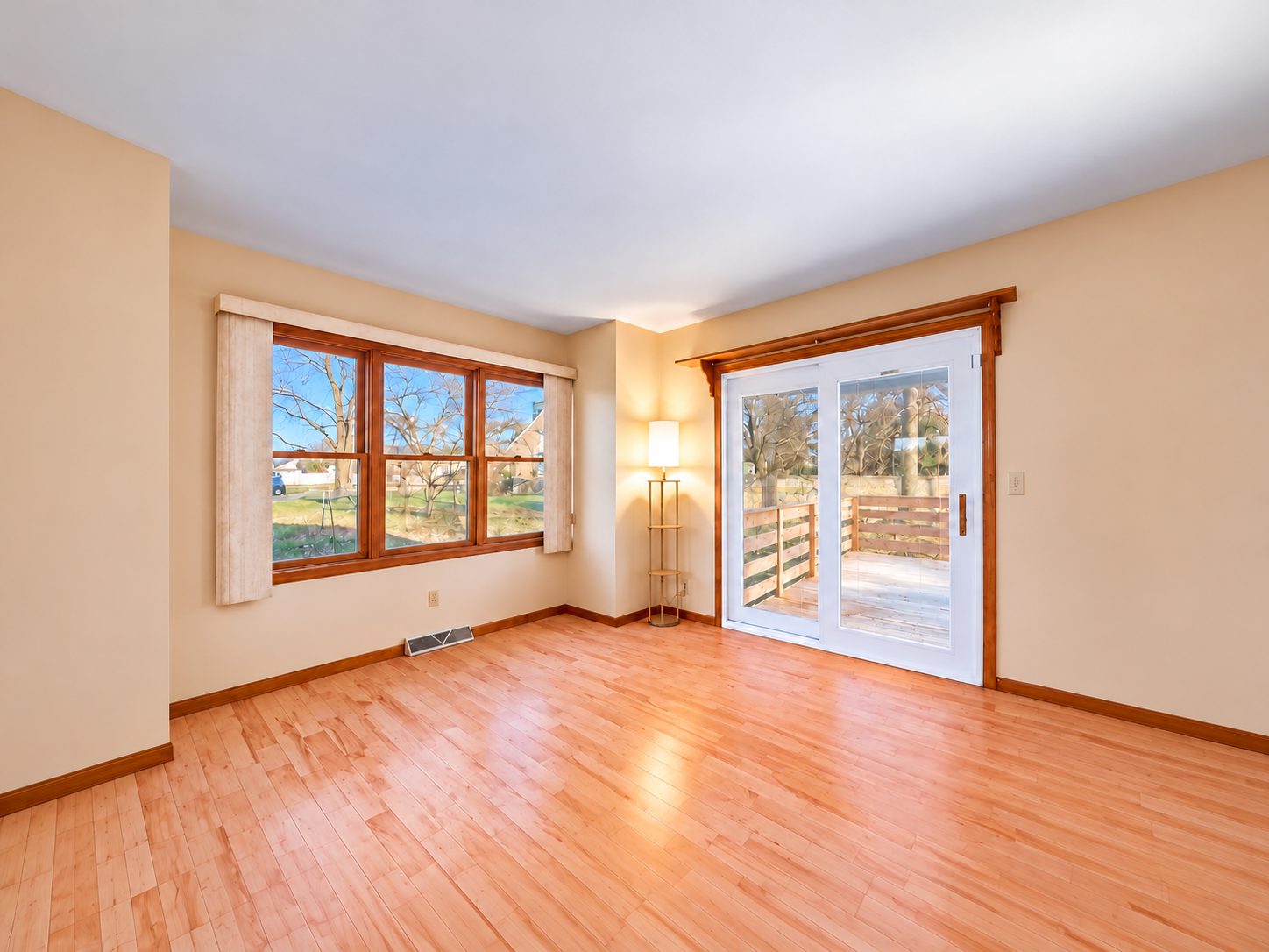 Sunroom before updates with wood-trimmed windows and oak flooring